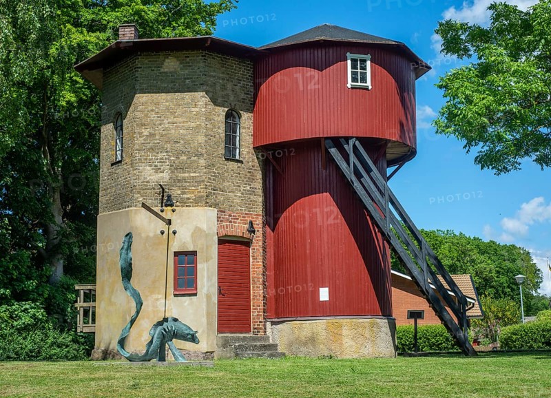 Historic pump house for filling up water on steam locomotives. In the foreground a statue of a mythological eel with horns. In Vollsjö, Skåne County, Sweden, Scandinavia, Europe