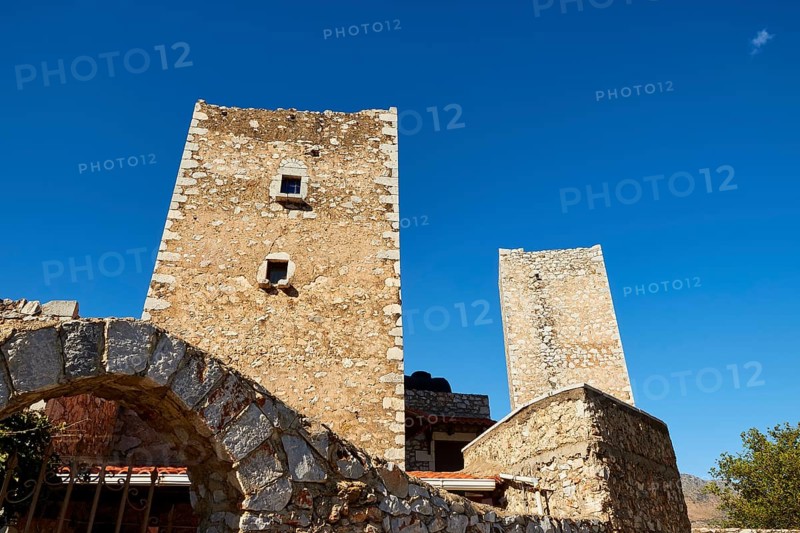 Stone towers of an ancient structure with an arch and blue sky in the background, Flomochori, residential towers village, Mani peninsula, Peloponnese, Greece, Europe
