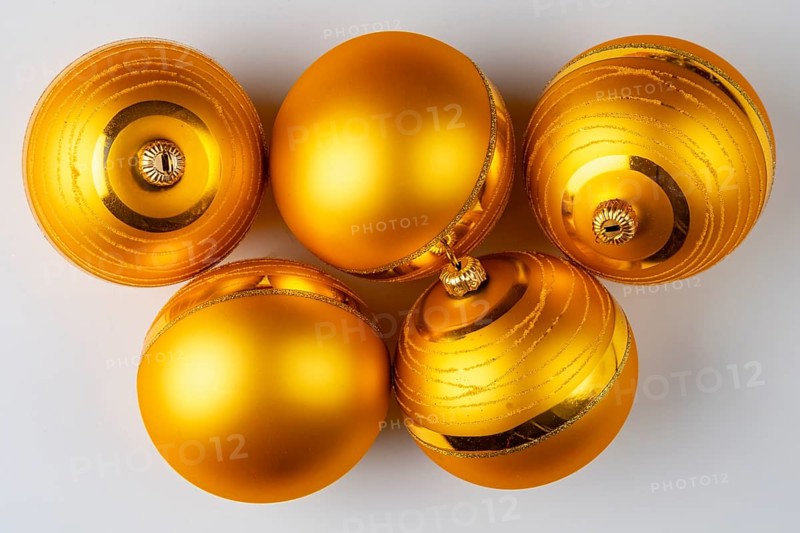 Five golden Christmas baubles lie on a white surface
