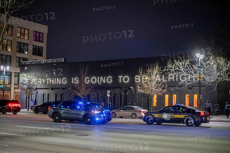 Detroit, Michigan - Police cars pass a sign reading 'Everything is Going to be Alright' at the Museum of Contemporary Art on Noel Night. The annual Noel Night at the beginning of the holiday season in Detroit features open houses by arts and cultural institutions, churches, and small businesses.