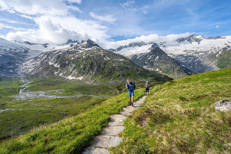 Two mountaineers on hiking trail in picturesque mountain landscape, mountain peak with snow and glacier Schwarzensteinkees, Hornkees and Waxeggkees, summit Schwarzenstein, Hornspitzen and Turnerkamp, valley Zemmgrund with Zemmbach, Berliner Höhenweg, Zillertal Alps, Tyrol, Austria, Europe