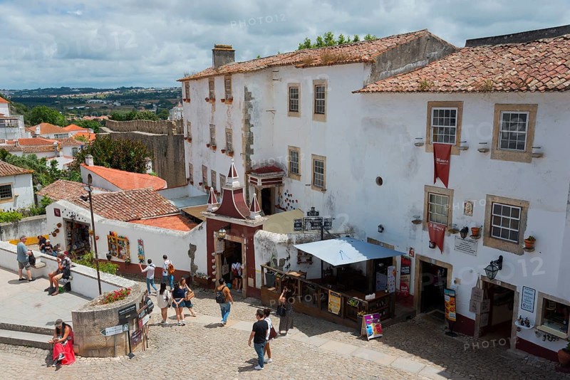 People walking through a cobbled historic city centre with white buildings and red roofs, view from Miradouro Porta, Largo de Padrão, Óbidos, Obidos, Oeste, Centro, Estremadura, Portugal, Europe