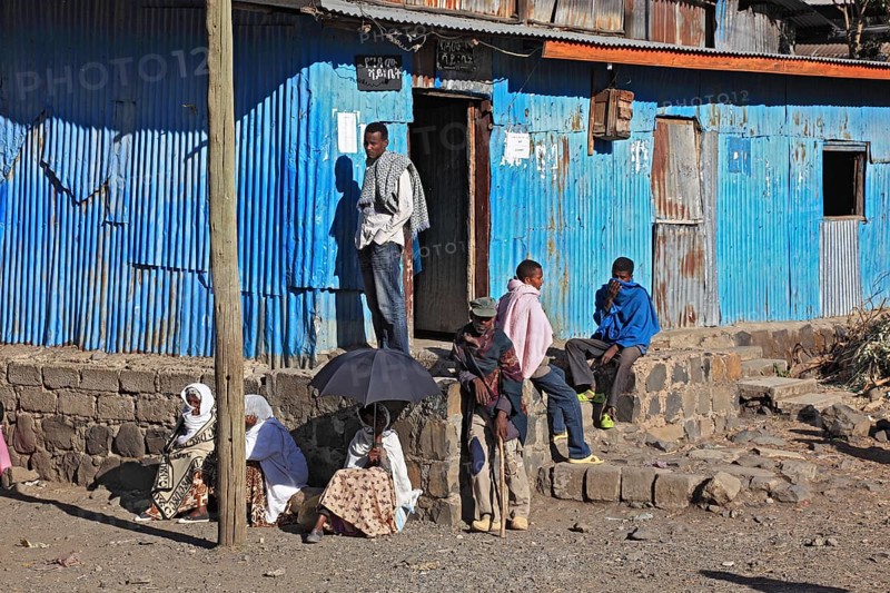 Europia district, locals waiting in front of a blue corrugated iron hut, Ethiopia, Africa