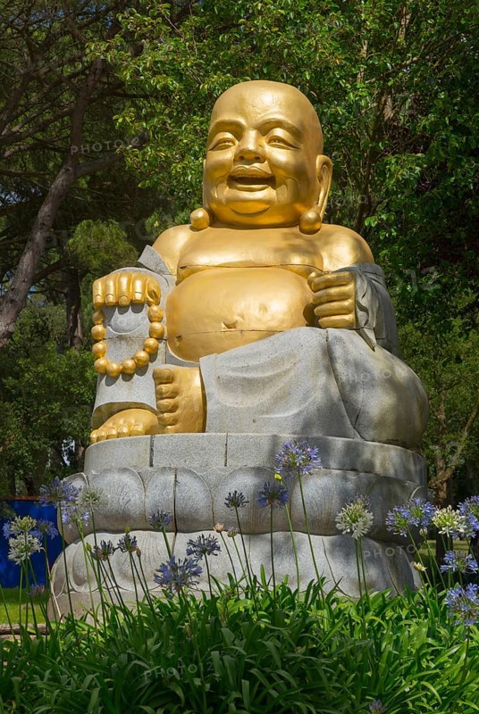 Golden Buddha statue, surrounded by flowers and green nature, radiates peace and spirituality under a clear sky, Bacalhôa, Bacalhoa Buddha Eden, Quinta dos Loridos, largest oriental garden in Europe, Bombarral, Oeste, Centro, Portugal, Europe
