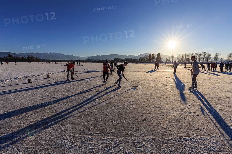 People playing ice hockey on a lake, evening light, sunbeams, Staffelsee, Murnau, foothills of the Alps, Bavaria, Germany, Europe