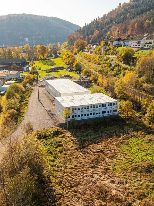 Warehouses surrounded by autumnal forest and village houses, refugee accommodation Beermiß, Calmbach, Black Forest, Germany, Europe