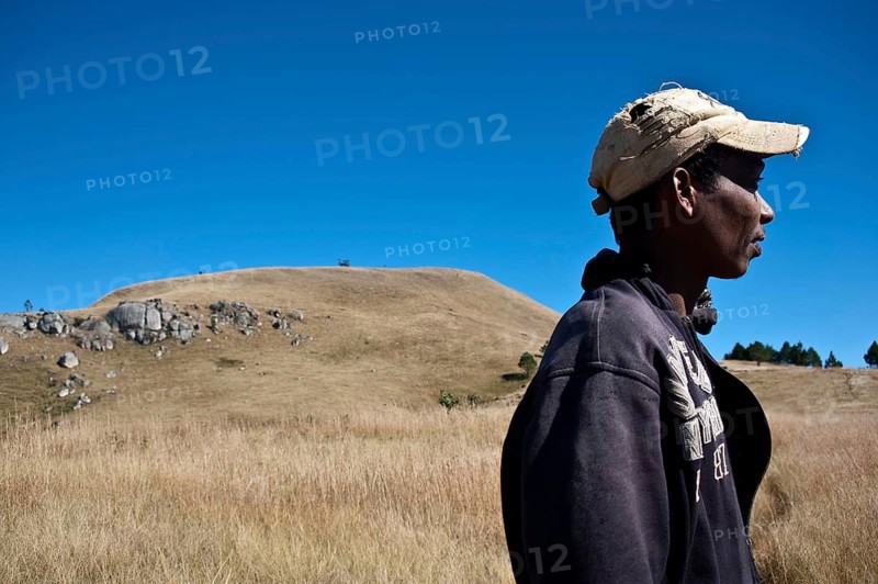 Portrait of a young man belonging to the Betsileo ethnic group. In the background, a sacred hill is visible. Near Ambositra, Madagascar, Africa