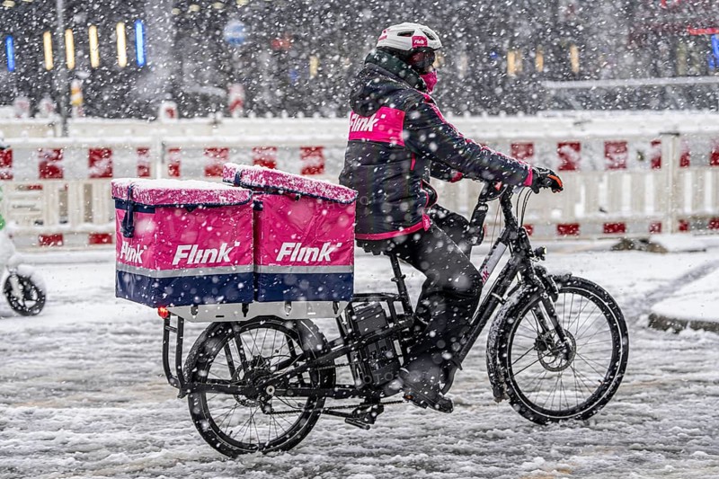 Winter weather, heavy snowfall, city centre traffic, courier of the delivery service Flink on bicycle in the snow, Essen, North Rhine-Westphalia, Germany, Europe