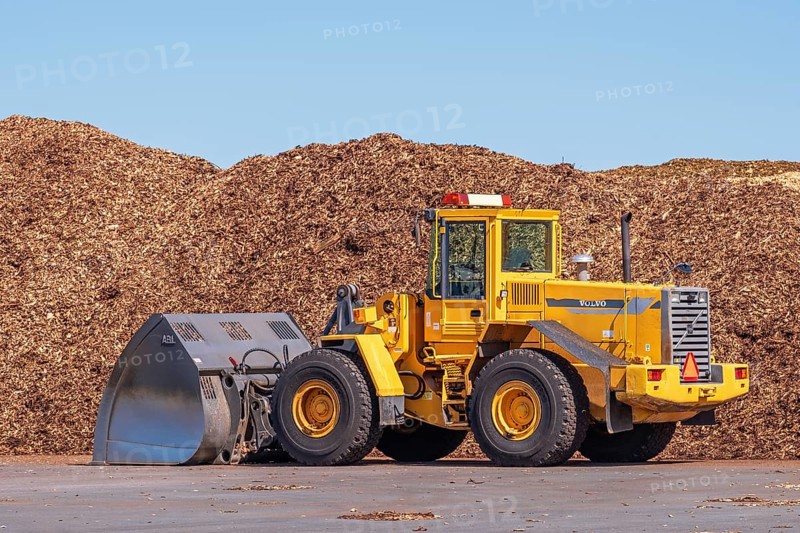 Front loader with a large bucket on a loading area for wood chips