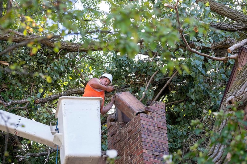 Detroit, Michigan, A worker dismantles a brick chimney after a storm with 70mph wind gusts blew down a 15-ton, 110-foot cottonwood. The tree cracked the chimney, leaving it leaning and threatening to crash through the home's roof