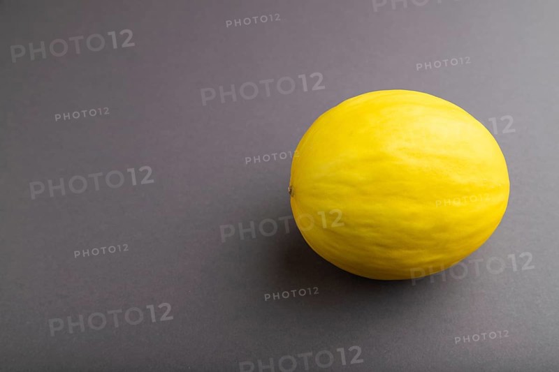 Ripe yellow melon on gray pastel background. Side view, copy space. harvest, healthy, vegan food, concept, minimalism