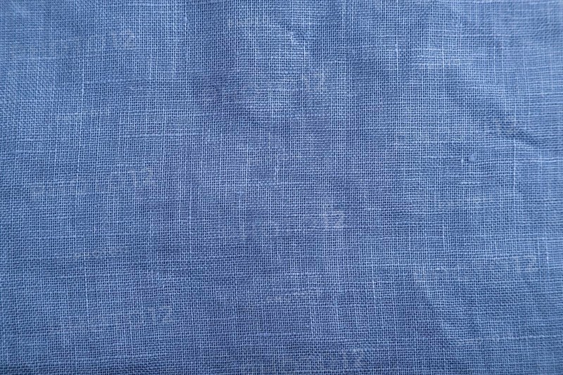 Fragment of smooth blue linen tissue. Top view, flat lay, natural textile background and texture