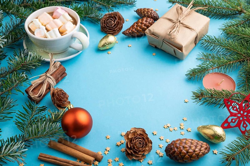 Christmas or New Year frame composition. Decorations, box, cinnamon, cones, fir and spruce branches, cup of coffee, on a blue paper background. Side view, copy space