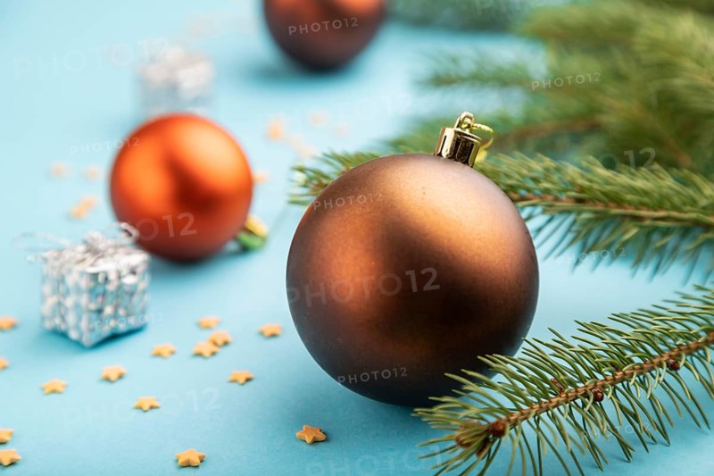 Christmas or New Year composition. Decorations, bronze balls, fir and spruce branches, on a blue paper background. Side view, close up, selective focus