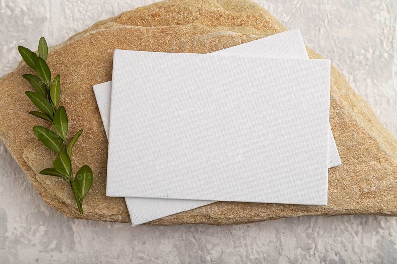 White paper business card, mockup with natural stone and boxwood branch on gray concrete background. Blank, flat lay, top view, still life, canvas, copy space