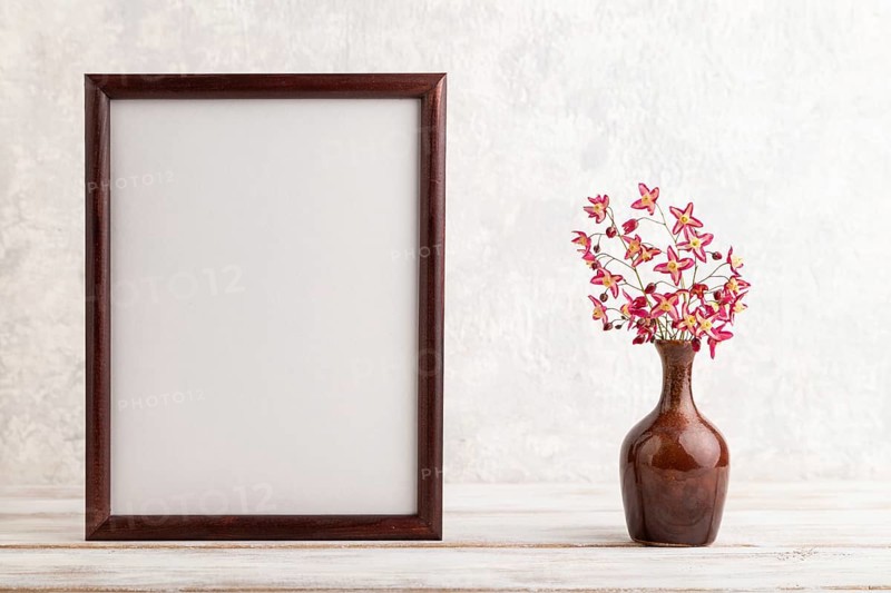 Wooden frame with purple barrenwort flowers in ceramic vase on gray concrete background. side view, copy space, still life, mockup, template, spring, summer minimalism concept