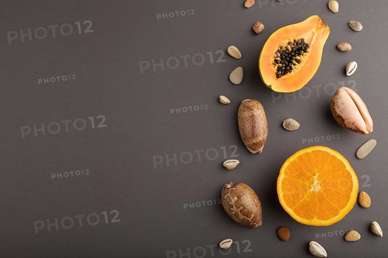 Ripe cut papaya, orange, seashells on gray pastel background. Top view, flat lay, copy space. Tropical, healthy food, vacation, holidays concept, minimalism