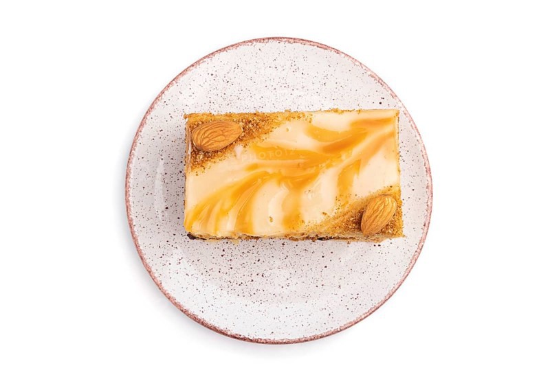 Honey cake with milk cream, caramel, almonds isolated on a white background. Top view, flat lay, close up