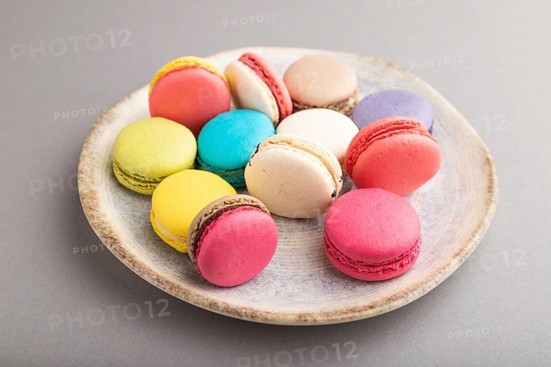 Multicolored macaroons on ceramic plate on gray pastel background. side view, close up, still life. Breakfast, morning, concept