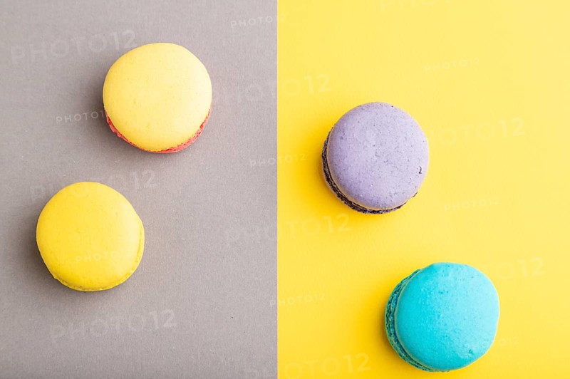 Yellow, purple and blue macaroons on trendy gray and yellow background. top view, copy space, close up, still life. Minimalism, morning, contrast concept