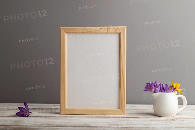 Beige wooden frame mockup with snowdrop crocus flowers on gray paper background. Blank, vertical orientation, still life, copy space