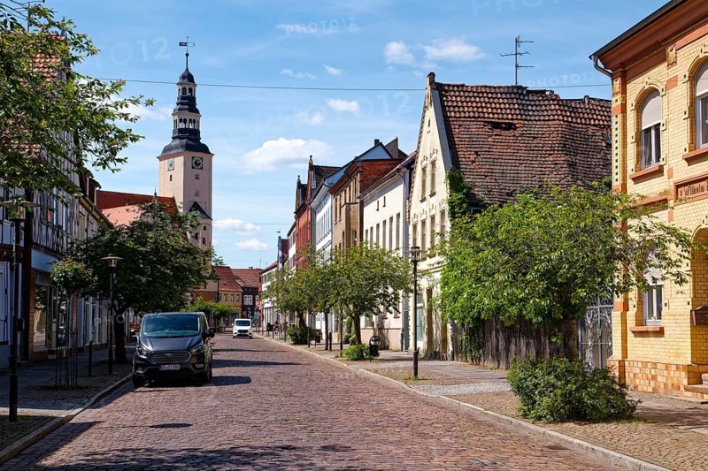 Residential and commercial buildings in Rudolf-Breitscheid-Straße, paved with cobblestones, in the old town centre of Gardelegen in the Altmark, with the town hall in the background. Hanseatic town of Gardelegen, Saxony-Anhalt, Germany, Europe