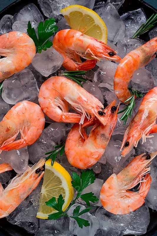 King shrimps, undivided, boiled-frozen, on ice, top view, selective focus, no people