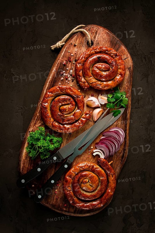 Fried spiral sausages, on a wooden board, top view, with spices, no people