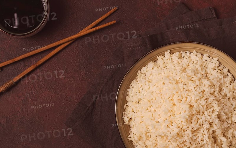 A plate of boiled rice, with wooden sticks, on a brown background, no people, selective focus, toned