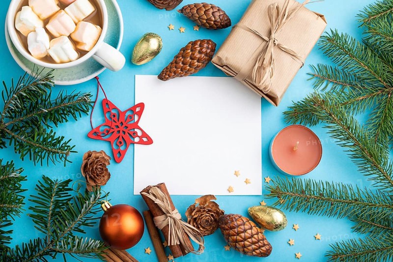 Christmas or New Year composition, template. Decorations, box, cinnamon, cones, fir and spruce branches, cup of coffee, on a blue paper background. Top view, copy space, flat lay