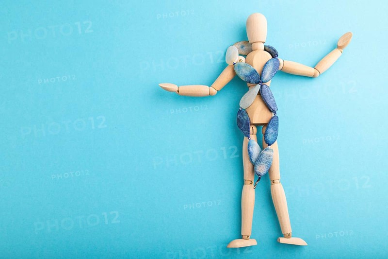 Wooden mannequin with blue agate beads on blue pastel background. copy space, isolated, luxury, bad taste, raunch, concept