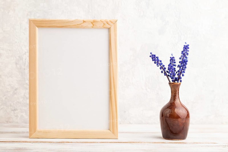 Wooden frame with blue muscari hyacinth flowers in ceramic vase on gray concrete background. side view, copy space, still life, mockup, template, spring, summer minimalism concept