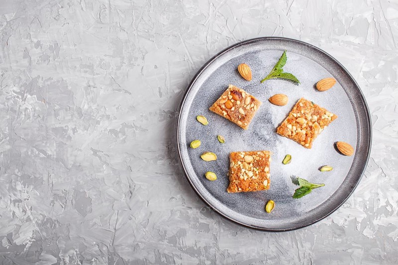 Traditional arabic sweets in gray ceramic plate on a gray concrete background. top view, copy space