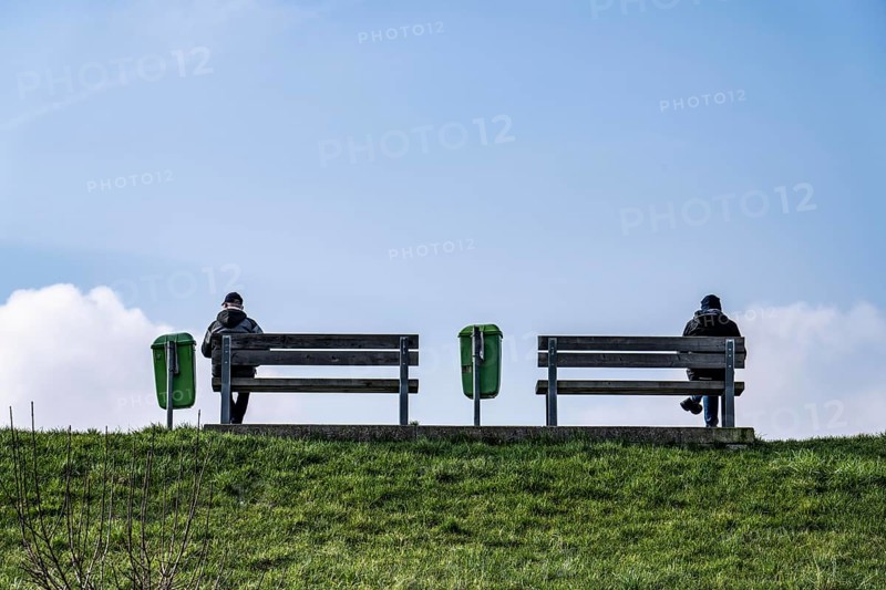 Benches on a dyke on the Weser in Bremerhaven, two people sitting symmetrically away from each other on the benches Bremen, Germany, Europe