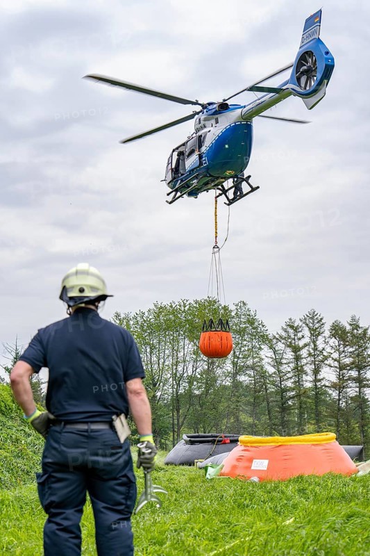 Forest fire fighting exercise of the Essen fire brigade, the water supply was rehearsed over longer distances to the scene of the operation, water basins were set up there from which a fire-fighting helicopter can take water, Airbus H145 of the North Rhine-Westphalia police aviation squadron with Bambi Bucket extinguishing water tank, North Rhine-Westphalia, Germany, Europe