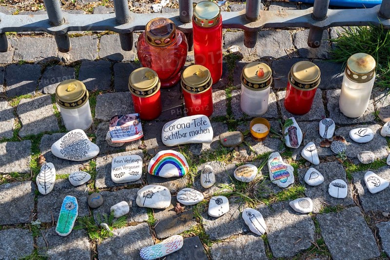 Candles and stones with inscriptions in memory of the dead of the corona pandemic, stickers from anti-vaccination campaigners, market square in the old town centre of Düsseldorf, North Rhine-Westphalia, Germany, Europe