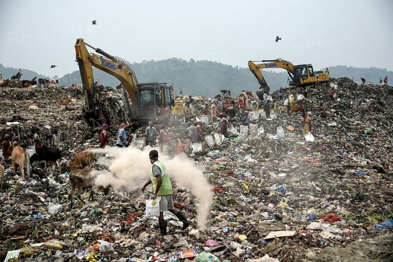 Municipality workers working with excavator as rag pickers searches for recyclable materials next to cows and birds at a garbage dumpsite, on the eve of World Environment Day, in Guwahati, Assam, India on 04 June 2022. World Environment Day is the biggest international day for the environment. Led by the United Nations Environment Programme (UNEP) on June 05 every year
