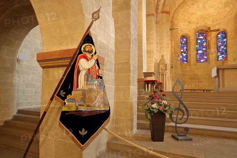 Interior view of the Romanesque basilica of St. Lubentius, chancel with flag of St. Lubentius, treble clef, clef, colourful stained glass windows, Dietkirchen, Limburg, Hesse, Germany, Europe