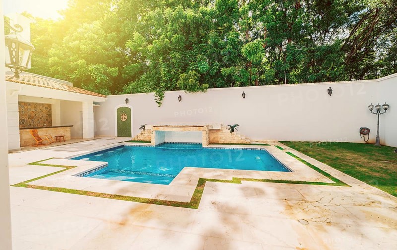 Homemade swimming pool surrounded by nature trees. Beautiful crystal clear swimming pool in a backyard