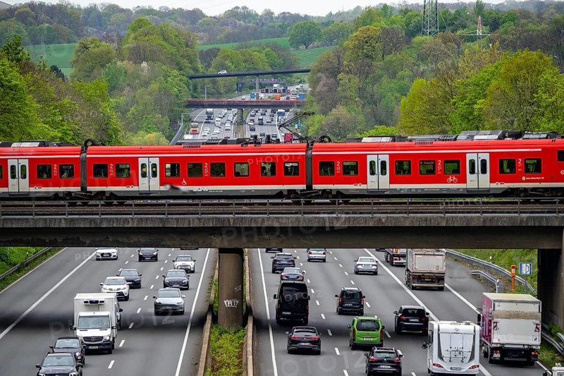 S-Bahn train crossing the motorway A3, traffic on 8 lanes, incl. the temporarily released hard shoulder, behind the motorway junction Hilden, view in north direction, near Erkrath, North Rhine-Westphalia, Germany, Europe