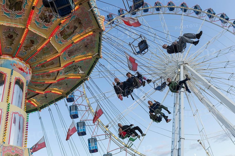 People swinging on a carousel in front of a Ferris wheel in sunny weather at a funfair, Europa Rad, Cannstadter Volksfest, Stuttgart-Bad Cannstadt, Baden-Württemberg