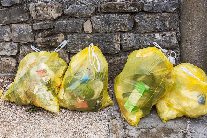 Close-up of translucent yellow plastic thrash bags filled with various discarded domestic garbage, Salona, Solin, Croatia, Europe