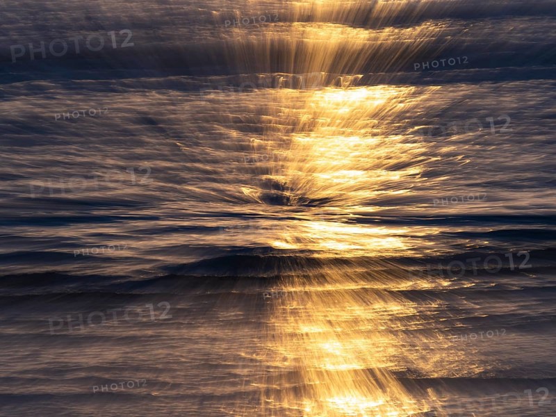Abstract image of the North Sea, an early evening mood with colorful yellow reflections of the sun, on the water as it reaches the beach, island of Texel, Holland