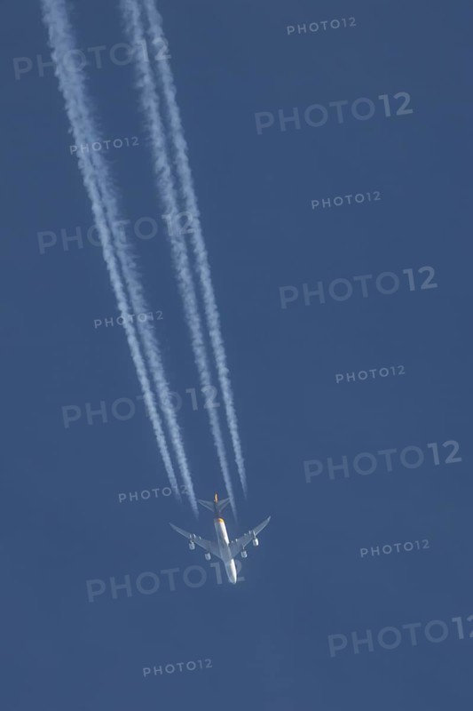 Boeing 747 jumbo jet cargo aircraft of UPS flying in a blue sky with a vapor trail or contrail behind, England, United Kingdom, Europe