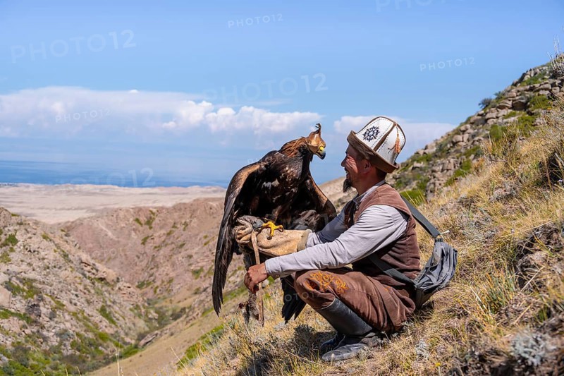 Traditional Kyrgyz eagle hunter with eagle in the mountains, near Kysyl-Suu, Kyrgyzstan, Asia