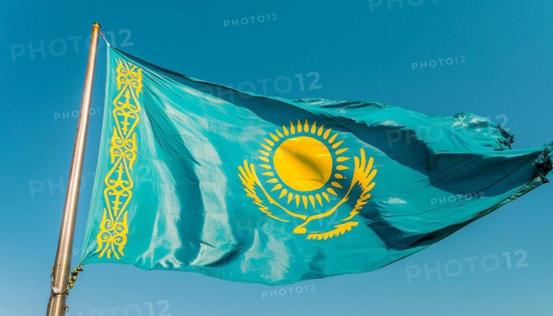 The flag of Kazakhstan flutters in the wind, isolated against a blue sky