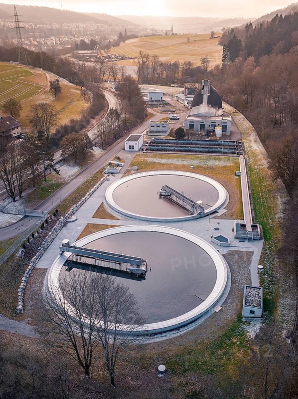 Aerial view of a sewage treatment plant focussing on the round clarifiers next to a forest, Nagold, Black Forest, Germany, Europe