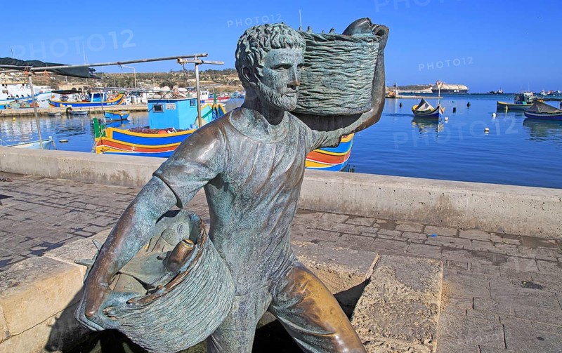 Fisherman statue sculpture in harbour at fishing village of Marsaxlokk, Malta, Europe