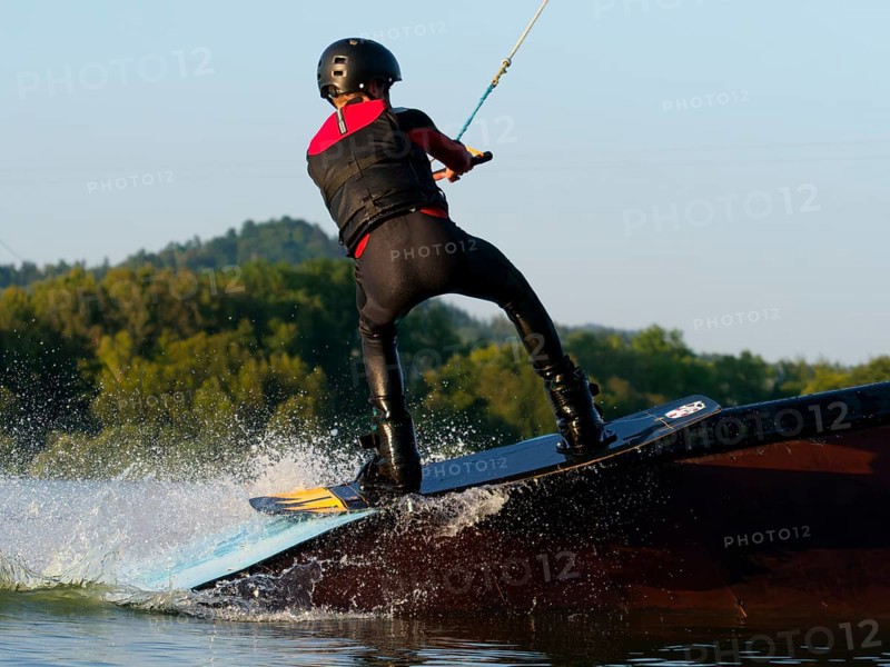 Young man with wakeboard on obstacle, water sports, water skiing in wakepark