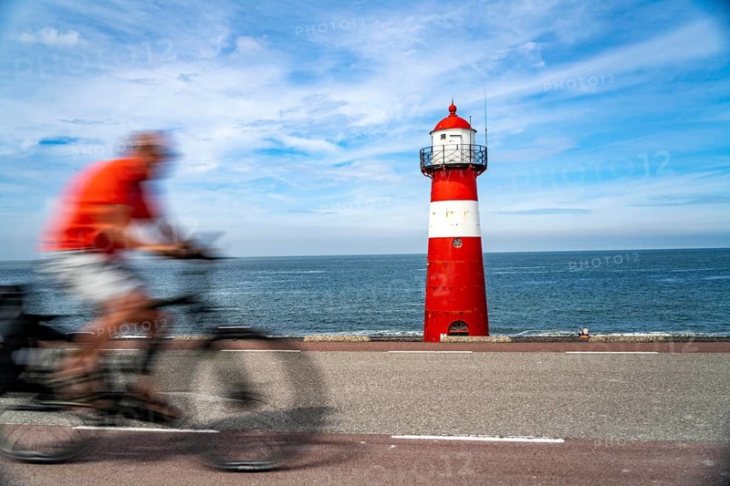 North Sea dyke near Westkapelle, Westkapelle Laag lighthouse, cyclists on the Zeeuwse Wind Route cycle path, province of Zeeland, Walcheren peninsula, Netherlands